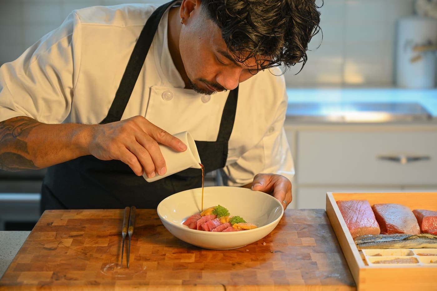 Chef Abe La pouring sauce over a plated dish